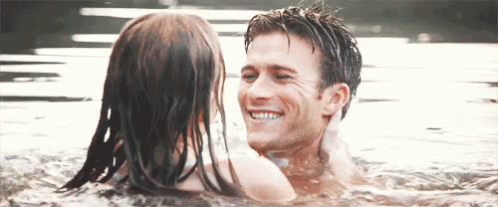 A Man And A Woman Are Swimming In The Water And Smiling At Each Other GIF