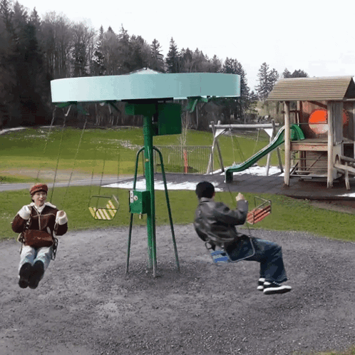 A Man And A Woman Are Swinging On A Green Swing Set GIF