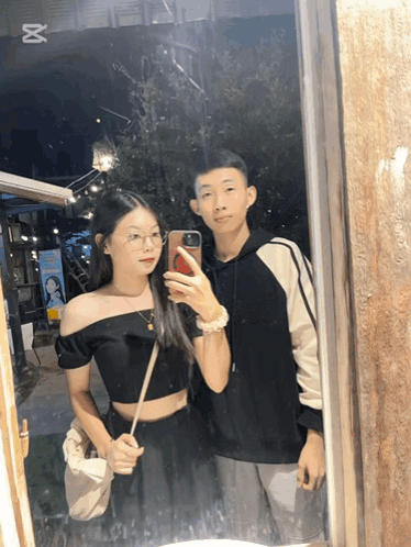 A Man And A Woman Are Taking A Picture In A Mirror GIF