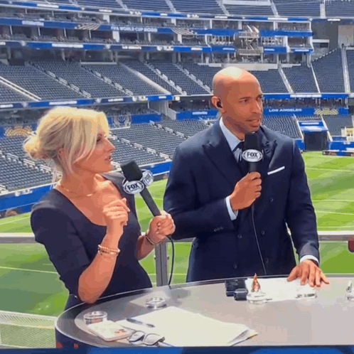 A Man And A Woman Are Talking Into Microphones That Say Fox On Them GIF