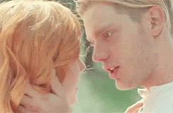 A Man And A Woman Are Touching Their Foreheads And Smiling At Each Other . GIF