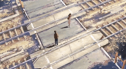 A Man And A Woman Are Walking Across A Train Track GIF