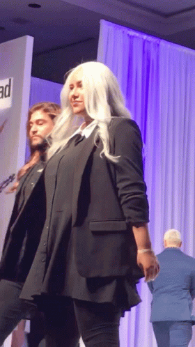 a man and a woman are walking down a runway at a fashion show