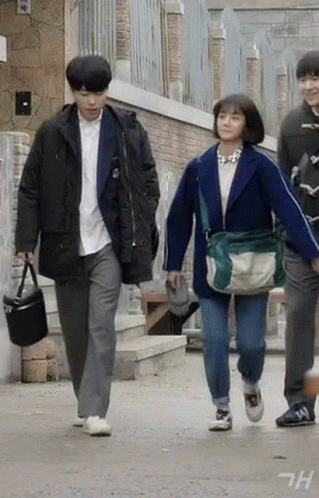 A Man And A Woman Are Walking Down A Street . GIF