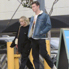 A Man And A Woman Are Walking Down The Street GIF