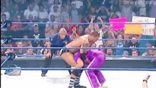 A Man And A Woman Are Wrestling In A Wrestling Ring With A Crowd Watching . GIF
