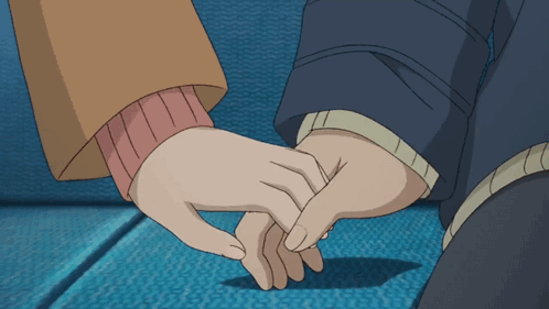 A Man And A Woman Holding Hands On A Blue Couch GIF