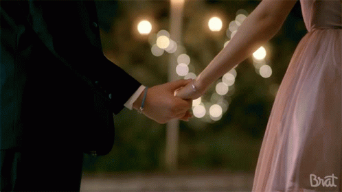 A Man And A Woman Holding Hands With The Word Brat On The Bottom Right GIF