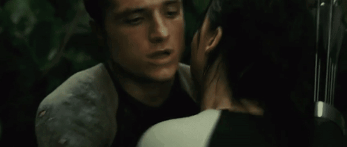 A Man And A Woman Hugging Each Other With A Bow And Arrow In The Background GIF