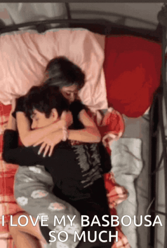 A Man And A Woman Hugging In Bed With The Words I Love My Basbousa So Much GIF