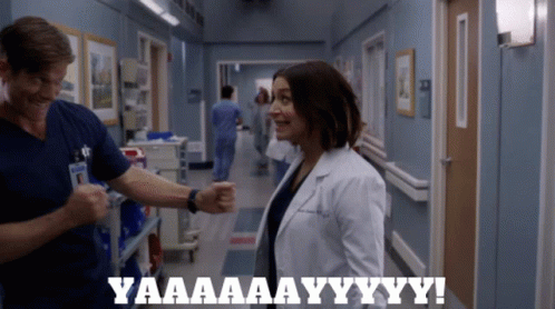 A Man And A Woman In A Hospital Hallway With The Words Yaaaa Aay Yy Yy GIF