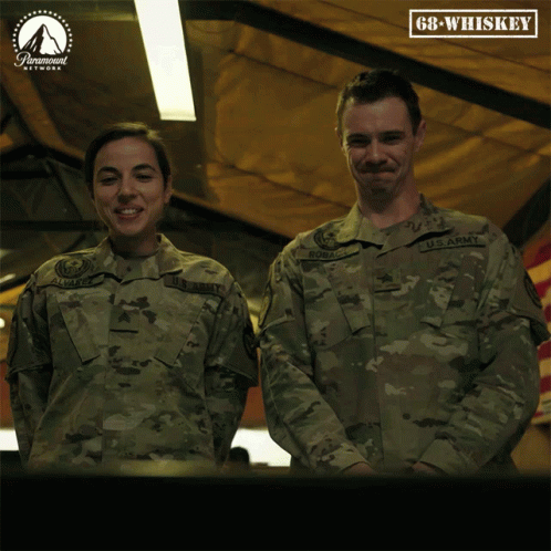 A Man And A Woman In Army Uniforms Are Standing Next To Each Other GIF