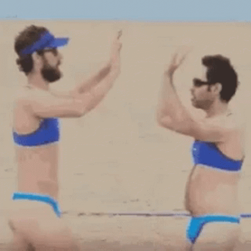 A Man And A Woman In Bikinis Are Walking On A Beach . GIF