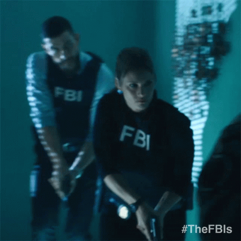 A Man And A Woman In Fbi Uniforms Are Standing In A Dark Room GIF