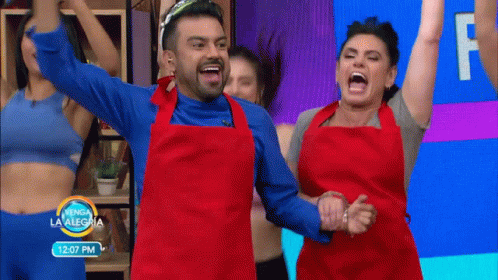 a man and a woman in red aprons are dancing in front of a sign that says 12:07 pm