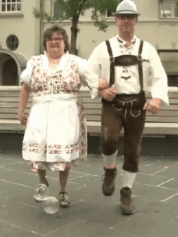 A Man And A Woman In Traditional Costume Are Dancing Together GIF