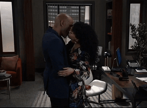 A Man And A Woman Kissing In A Living Room GIF