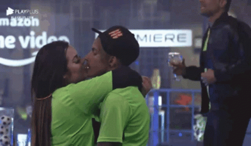A Man And A Woman Kissing In Front Of A Sign That Says Miere GIF
