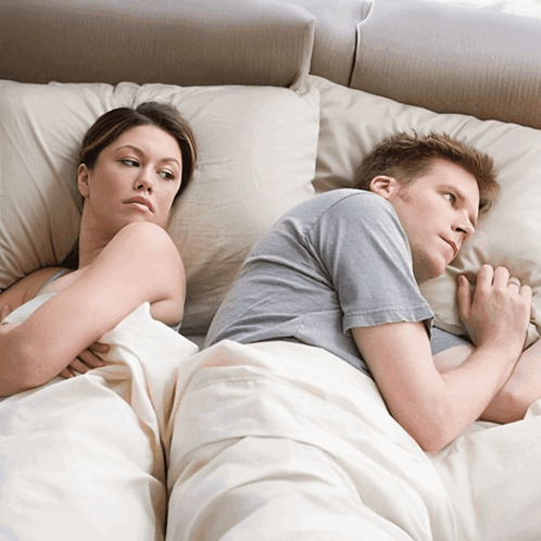 A Man And A Woman Laying Back To Back On A Bed GIF