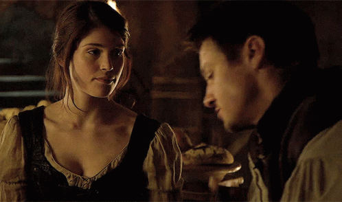 A Man And A Woman Look At Each Other In A Dark Room GIF