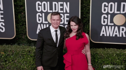 A Man And A Woman Pose On The Red Carpet At The Golden Globe Award GIF