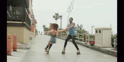 A Man And A Woman Rollerblading On A Sidewalk With The Man Holding The Woman 'S Hand GIF