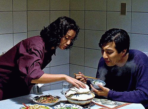 A Man And A Woman Sit At A Table Eating Food GIF