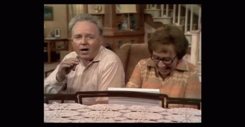 Man And Woman Sitting At Table Looking At Something GIF