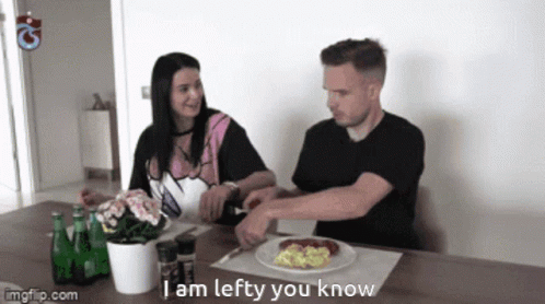 A Man And A Woman Sit At A Table With A Plate Of Food And The Words I Am Lefty You Know On The Table GIF