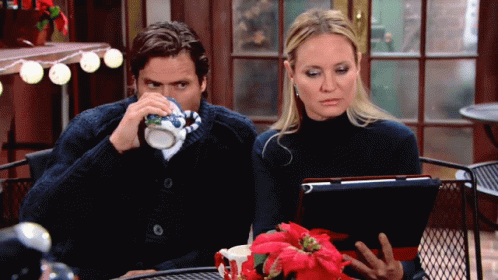 A Man And A Woman Sit At A Table With A Tablet GIF