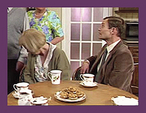 A Man And A Woman Sit At A Table With Cups And Saucers Of Tea GIF