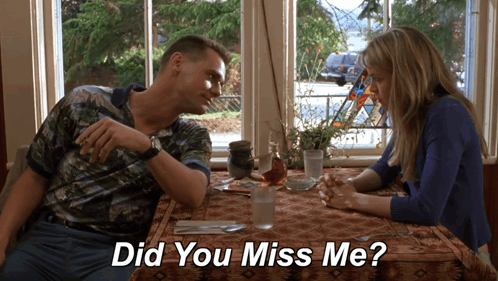 A Man And A Woman Sit At A Table With The Words " Did You Miss Me " Below Them GIF