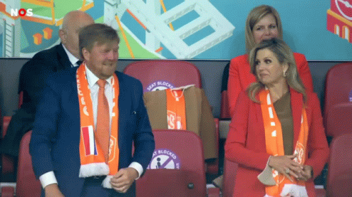 a man and a woman sit in a stadium with seat blocks written on the backs of their seats