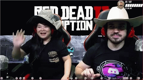 A Man And A Woman Sit In Front Of A Red Dead Redemption Screen GIF