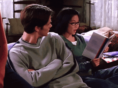 A Man And A Woman Sit On A Couch Reading Books GIF