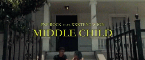 A Man And A Woman Sit On The Steps Of A House With The Words Middle Child Written Above Them GIF
