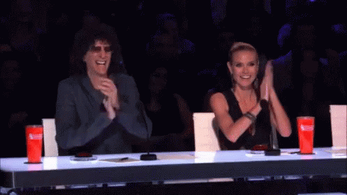 A Man And A Woman Sitting At A Table Clapping GIF