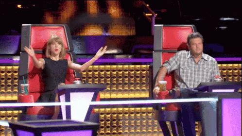 A Man And A Woman Sitting In Red Chairs With Their Arms Outstretched GIF