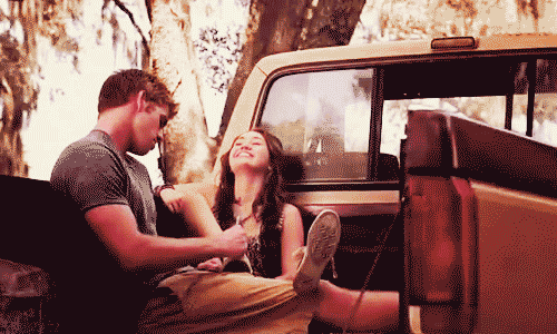 A Man And A Woman Sitting In The Back Of A Truck GIF