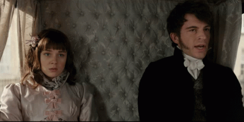 A Man And A Woman Sitting Next To Each Other In A Room GIF