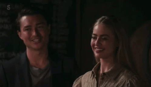 A Man And A Woman Sitting Next To Each Other With The Number 5 On The Bottom Left GIF