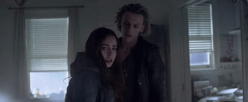 A Man And A Woman Standing In A Dark Room GIF