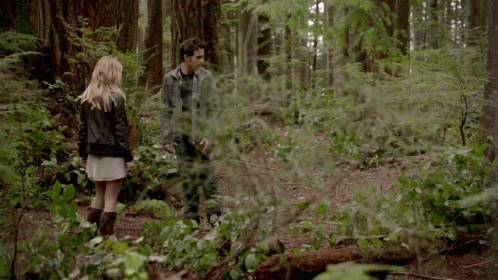 A Man And A Woman Standing In A Forest GIF
