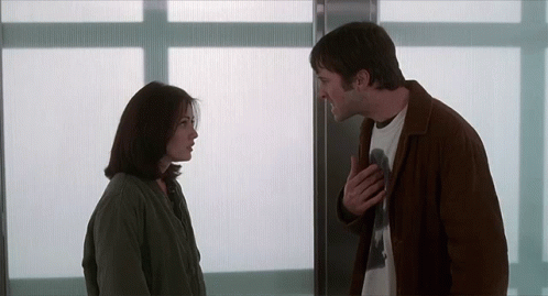 A Man And A Woman Standing Next To Each Other GIF