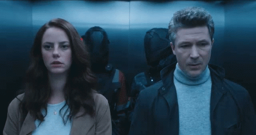 A Man And A Woman Standing Next To Each Other In A Dark Room GIF