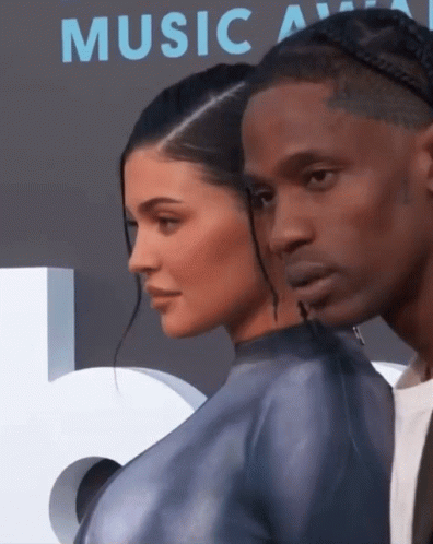 A Man And A Woman Standing Next To Each Other In Front Of A Music Awards Sign GIF