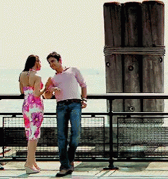 A Man And A Woman Standing Next To Each Other On A Balcony GIF
