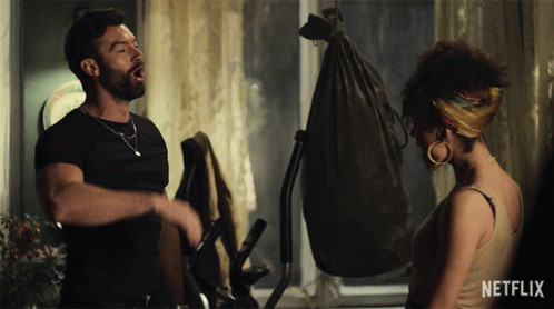A Man And A Woman Standing Next To Each Other With A Netflix Logo In The Corner GIF