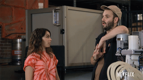 Man And Woman Standing Next To Netflix Logo GIF