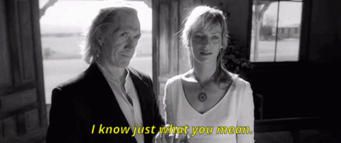 A Man And A Woman Standing Next To Each Other With I Know Just What You Mean Written In Yellow GIF
